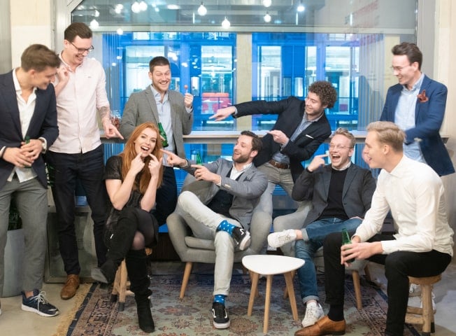 8 men laughing and pointing a woman